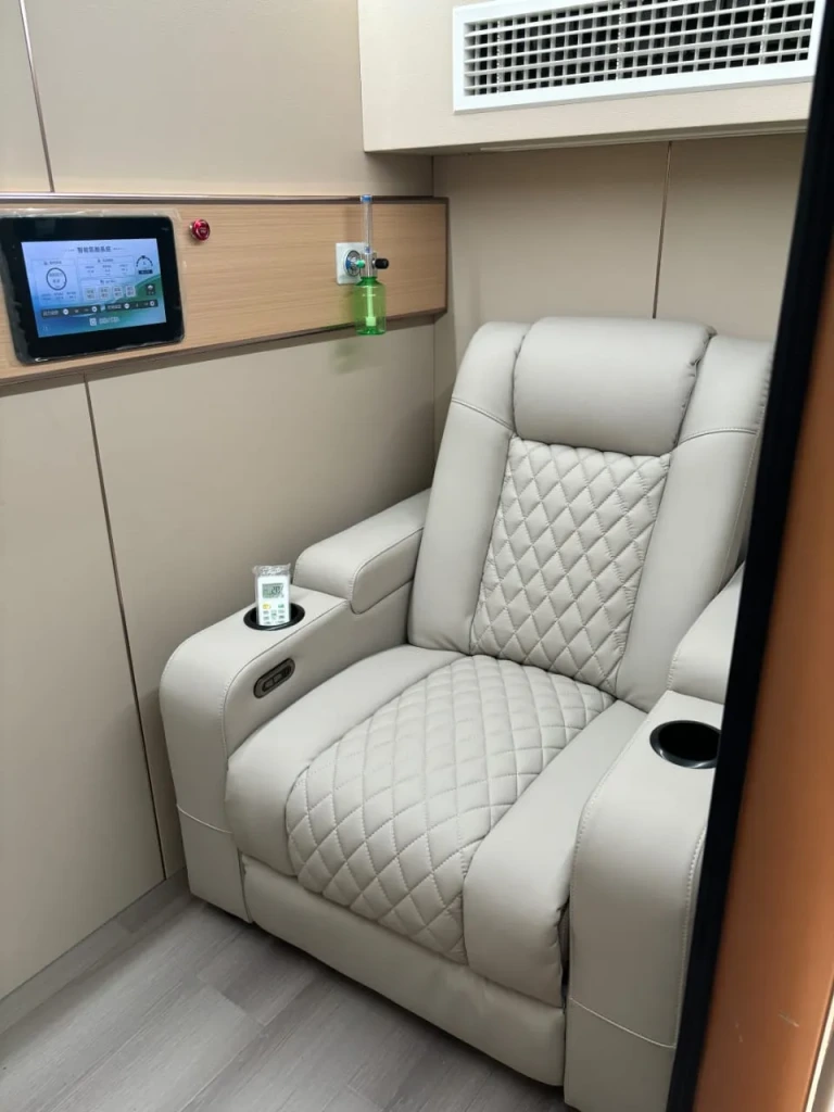 Luxury hyperbaric oxygen chamber interior with reclining chair and control panel